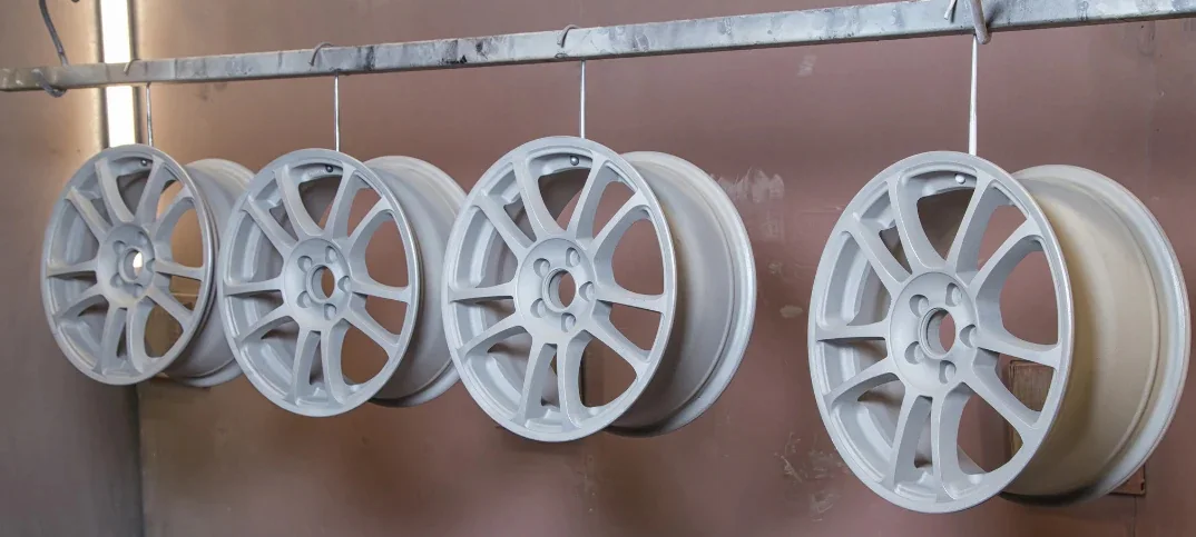 Freshly powder-coated wheels in a professional finishing workshop