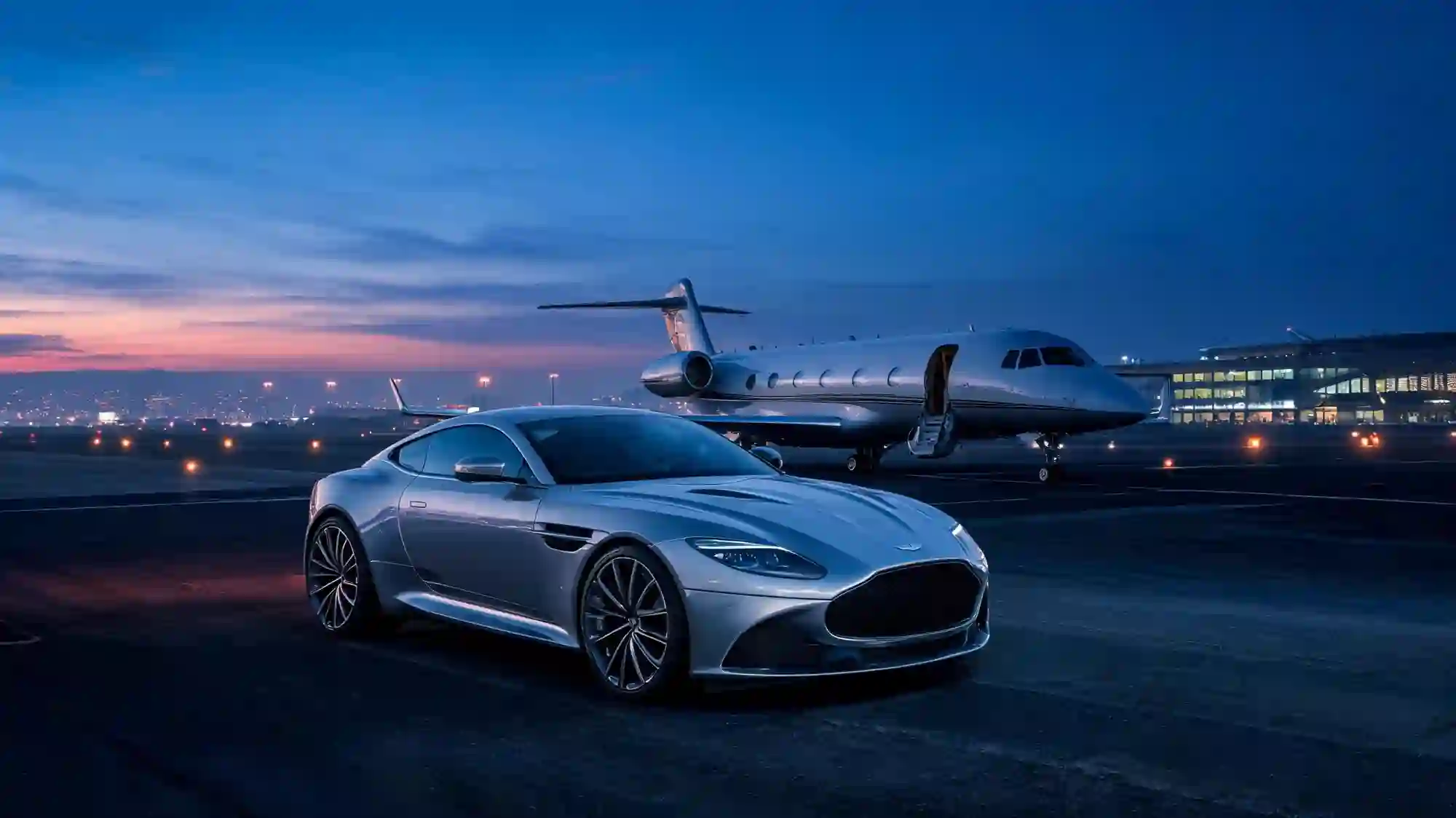 A luxury car delivered on a private jet tarmac at twilight