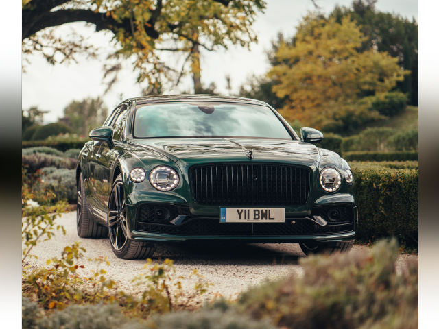 A green Bentley Flying Spur in a garden setting